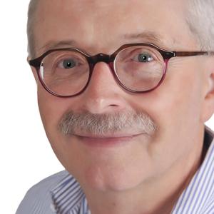 Boyd is an older man, with short white hair and a grey moustache. He has dark, round-rimmed glasses, and looks straight into the camera