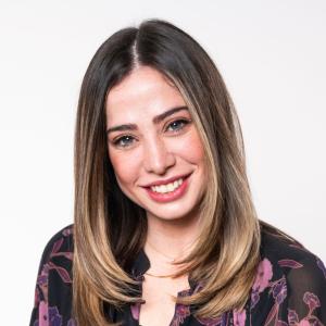Victoria is a light-skinned woman, with long brown hair and dark eyes. She wears a pink patterned shirt and smiles at the camera.