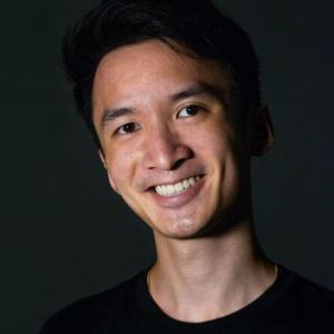 Kevin has short black hair, and smiles widely to the camera