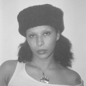 A black and white photo of a black women wearing a fur hat looks at the camera