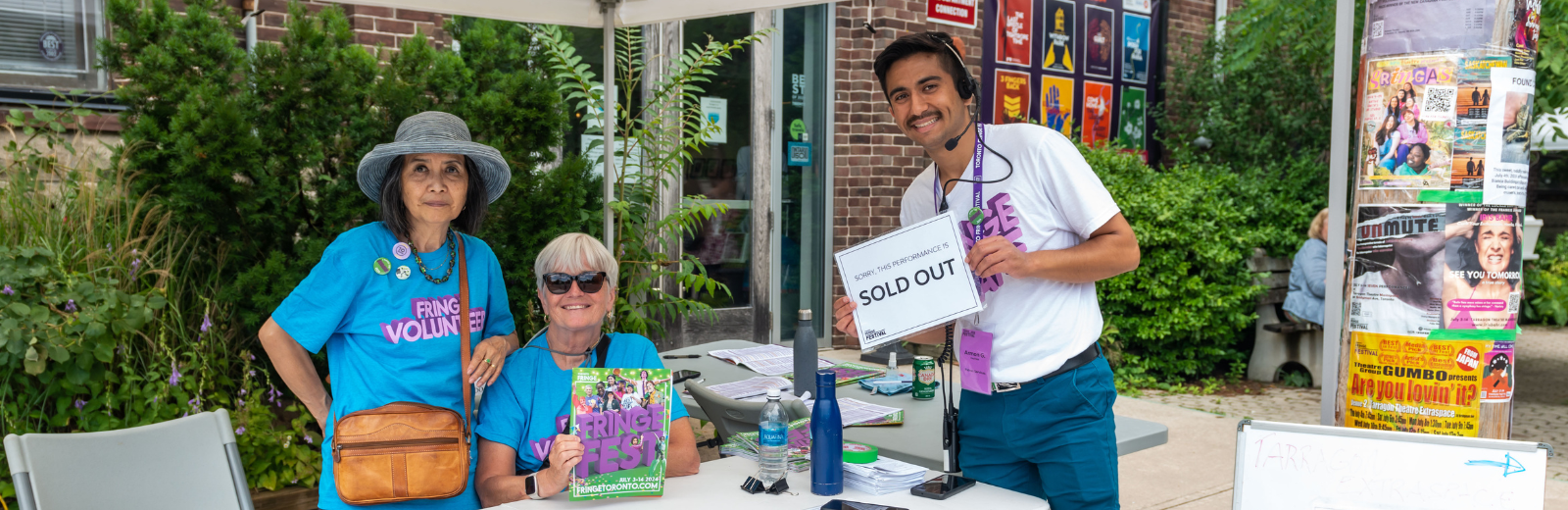 Staff and volunteers at a Fringe venue hold up a "sold out" sign